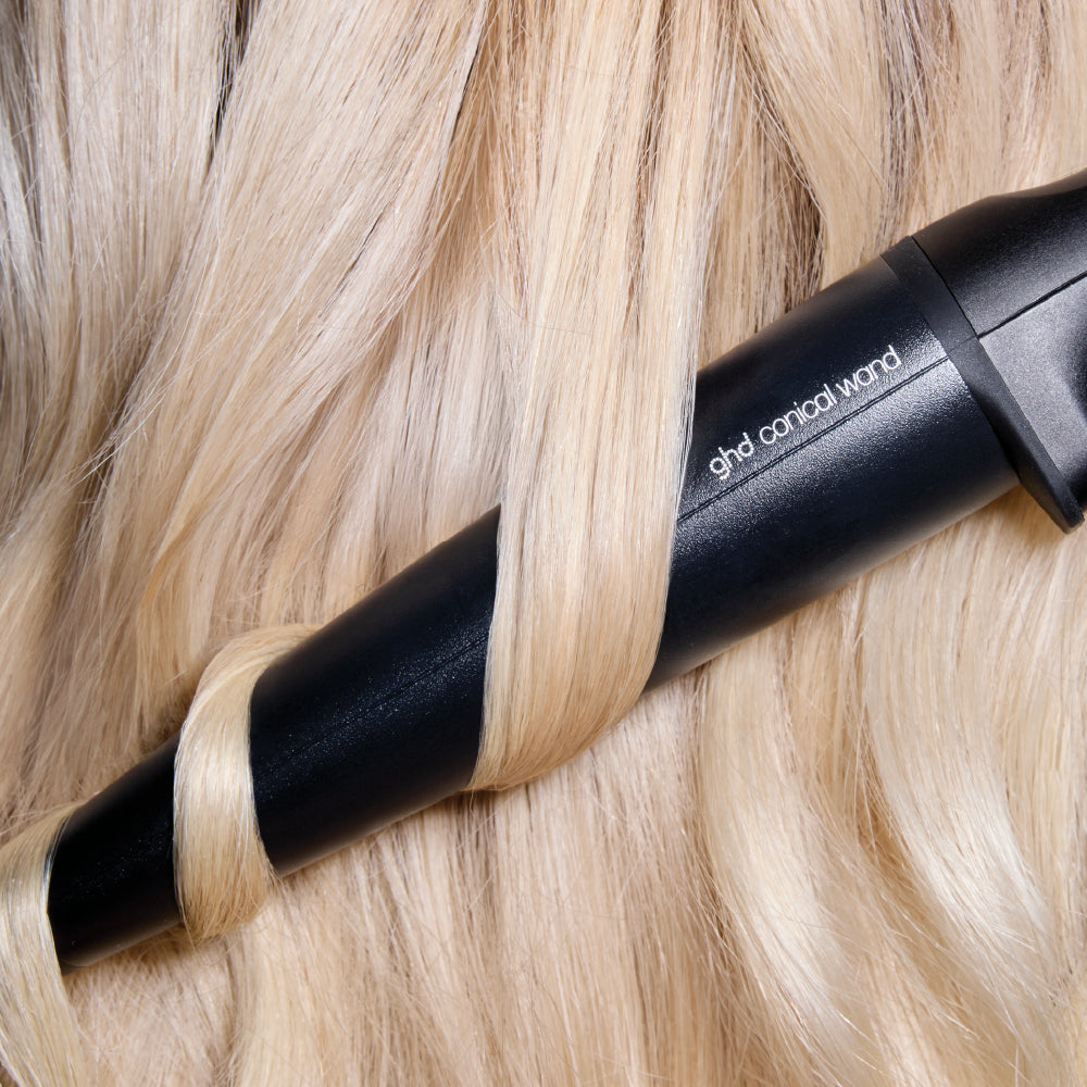 Black hair straightener being used on blonde hair